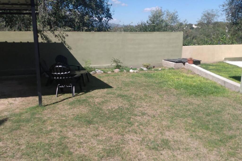 a chair sitting in the grass in a yard at Monoambiente amplio con pileta in Cosquín