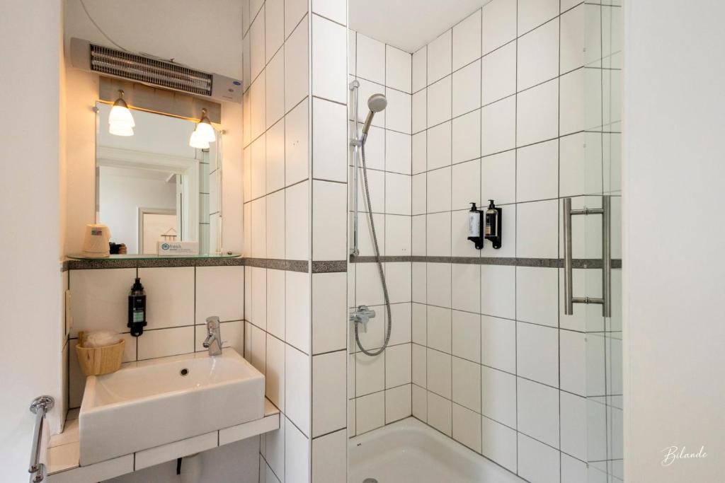 ein weißes Bad mit einer Dusche und einem Waschbecken in der Unterkunft la chocolaterie in Roly