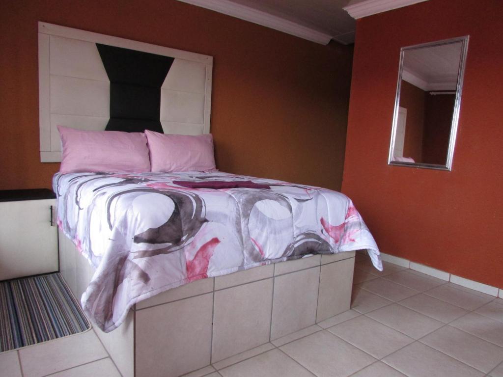 um quarto com uma cama grande e almofadas cor-de-rosa em Cozy Queen-Bed Apartment in Hammanskraal 