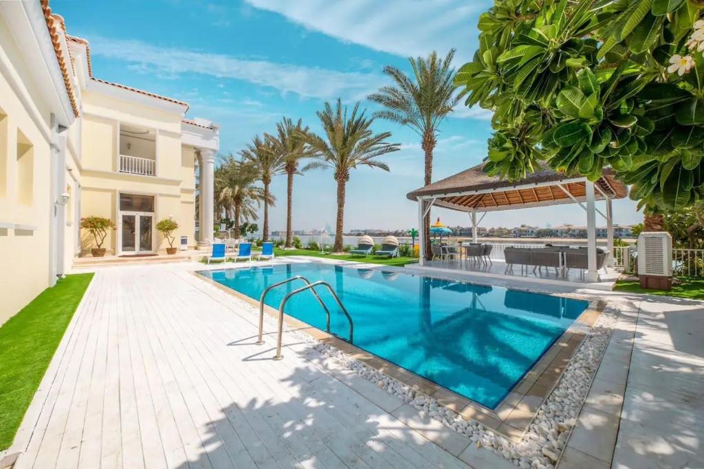 a swimming pool in the backyard of a house with palm trees at Pristine Paradise Villa In Palm Jumeirah in Dubai