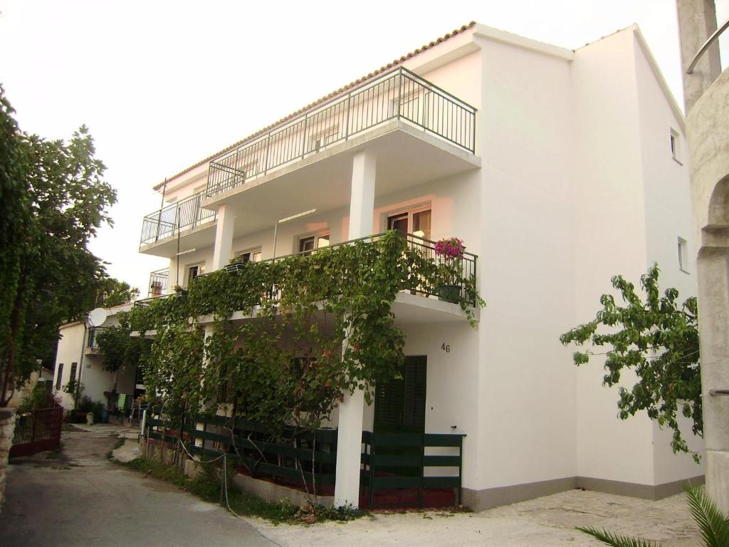 a white house with a balcony and ivy at Apartment Kosor in Zaboric