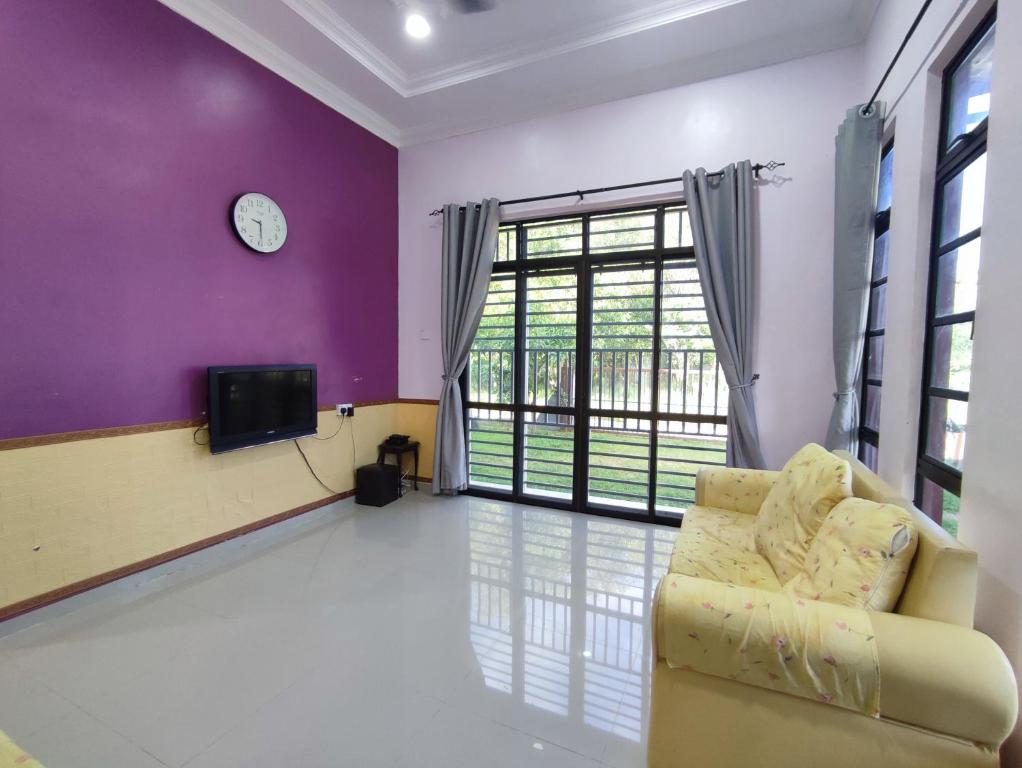 ein Wohnzimmer mit einem Sofa und einem TV in der Unterkunft NikNa Homestay Batu Rakit - WIFI in Kampong Ru Tujoh