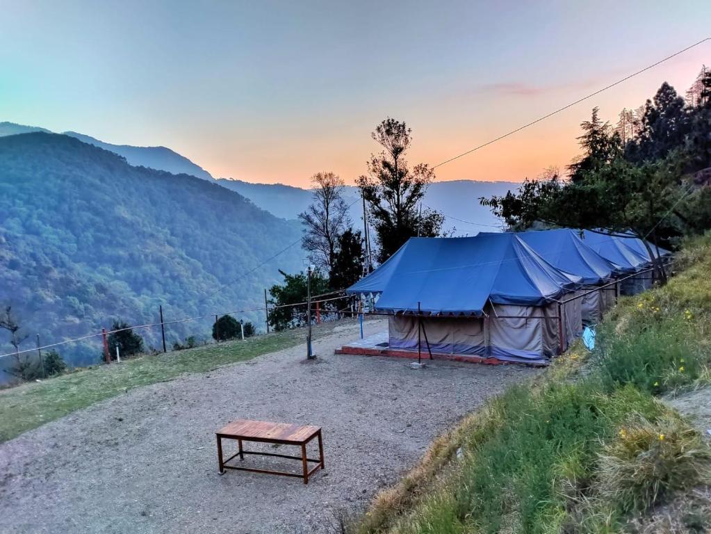 Valley view camps &cottages في ناينيتال: خيمة جلوس فوق تلة مع طاولة