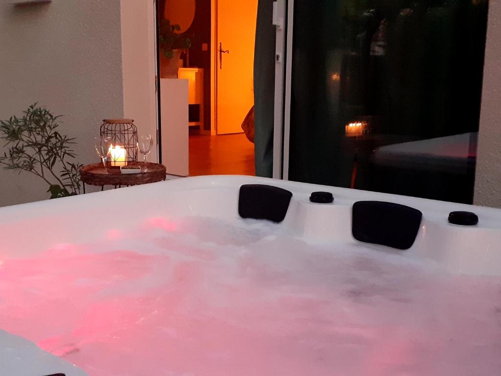 a bath tub filled with pink water with a candle at L escapade in Saint-Siffret