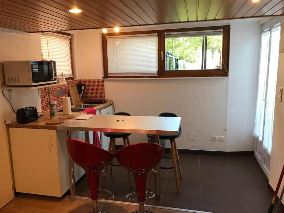 een keuken met een tafel en wat rode krukken bij Studio 1 à 4 pers, proche Strasbourg, Europa-Park, Colmar in Erstein