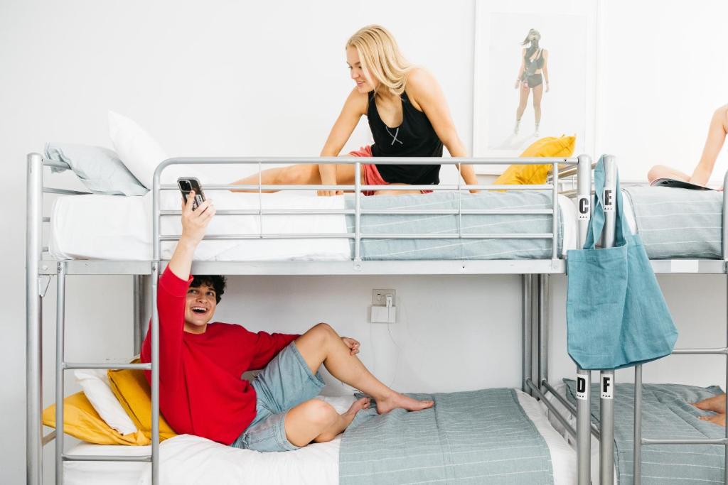 un homme prend une photo d'un groupe de personnes sur des lits superposés dans l'établissement The Village Surry Hills, à Sydney