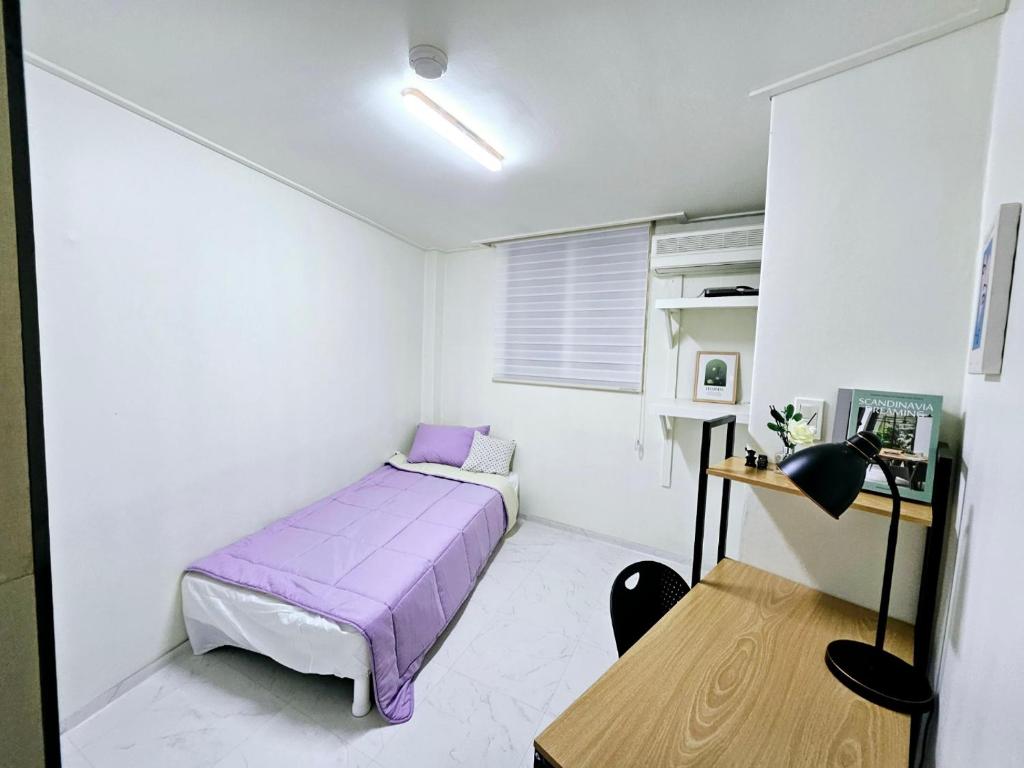 um pequeno quarto com uma cama roxa e uma secretária em k histay jongan em Seul
