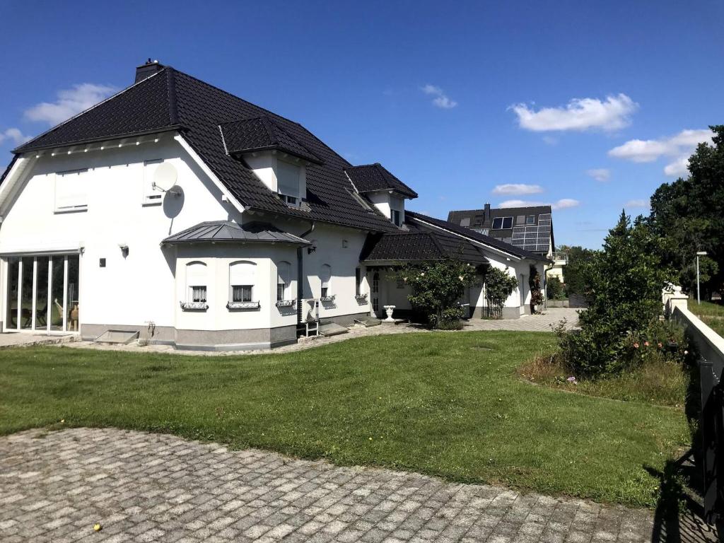 uma casa branca com um telhado preto em Room in Apartment - Haus Im Grunen House in the green em Neuzelle