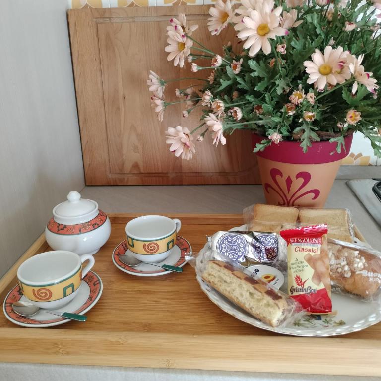 una mesa con un plato de comida y tazas y una planta en Casavacanze Sottocolle, en Valmorea