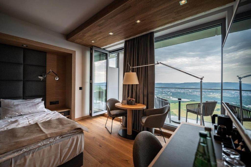 ザールフェルトにあるKulmberghaus Resortのベッドと大きな窓が備わるホテルルームです。
