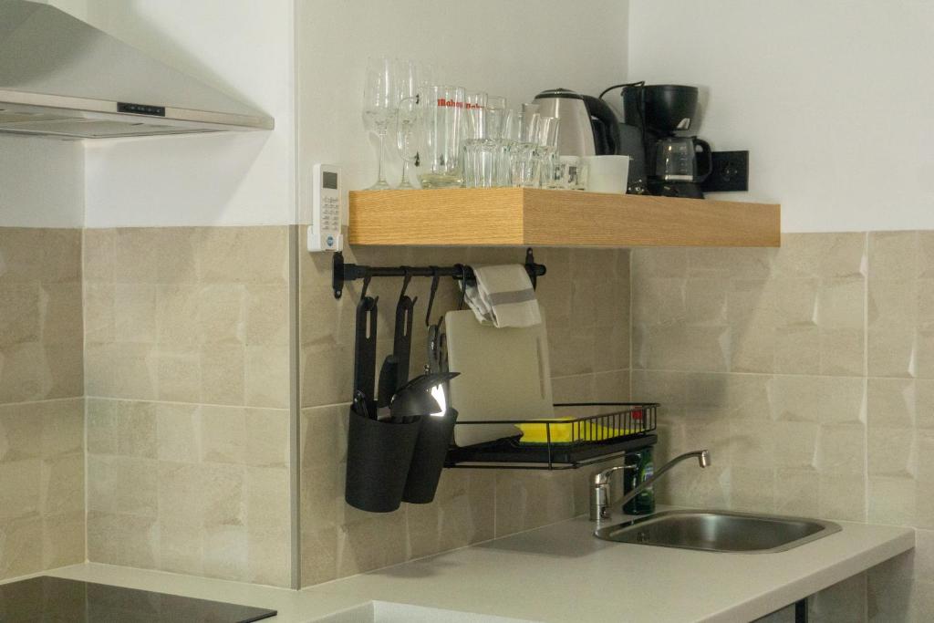 a kitchen counter with a sink and a shelf with utensils at Apartamentos La Ruta in Calpe