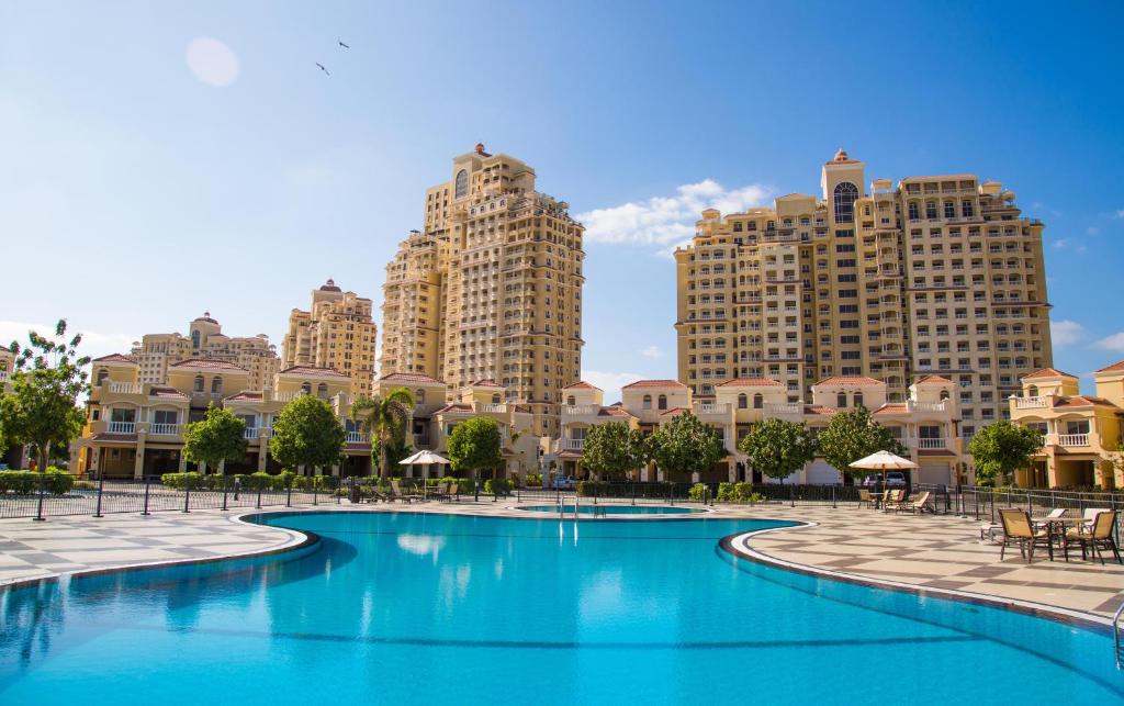 a pool in front of some tall buildings at Hala Holiday Homes - Al Hamra Village, RAK in Ras al Khaimah