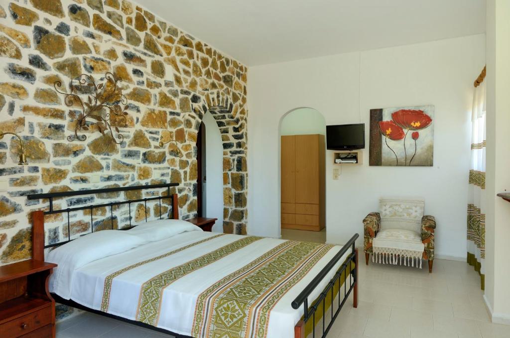 a bedroom with a stone wall with a bed at Albatros Studios & Apartments in Plakias