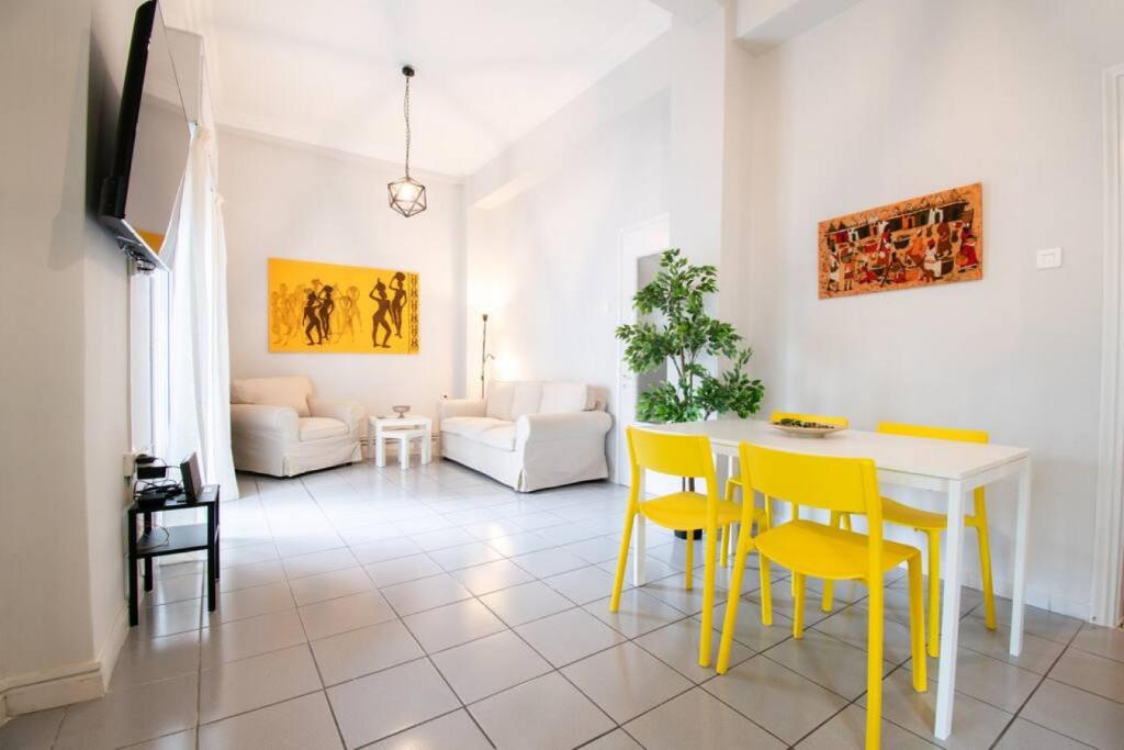 a living room with a white table and yellow chairs at Chic Kastella Apt by Mikrolimano in Piraeus