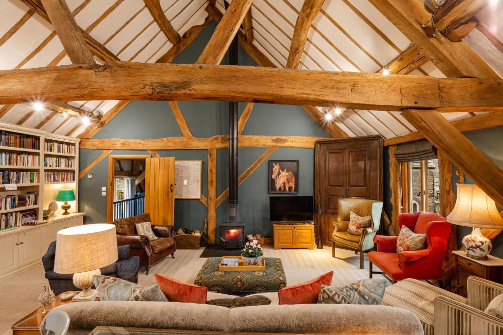 a large living room with wooden ceilings and a fireplace at Meadow End Barn in Dorstone