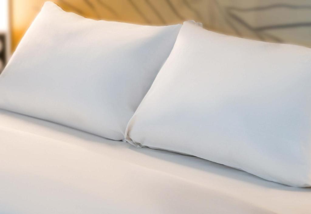 a pair of white pillows on a bed at B&amp;B HOTEL Massieux Genay in Genay
