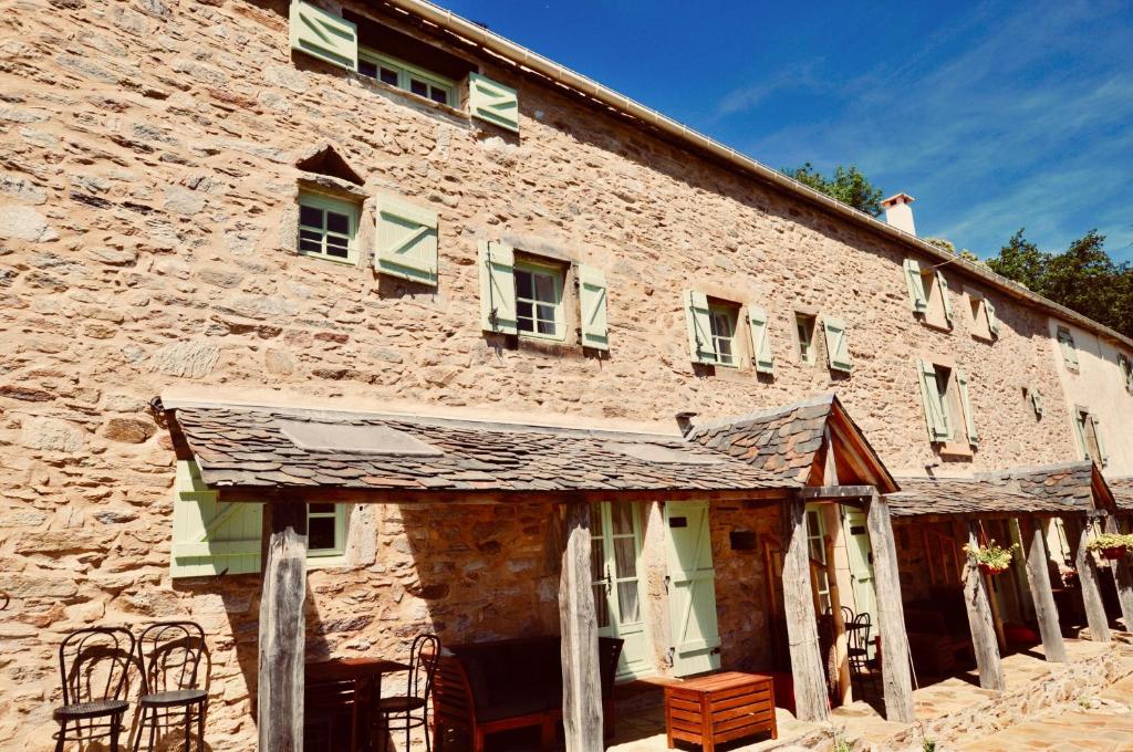 un antiguo edificio de piedra con ventanas con contraventanas verdes en Les Coumayres en Riols