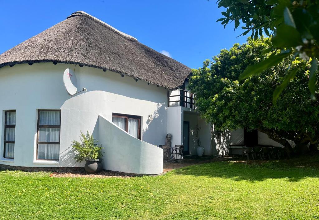 a large white house with a thatched roof at Anchor Drift in St Francis Bay