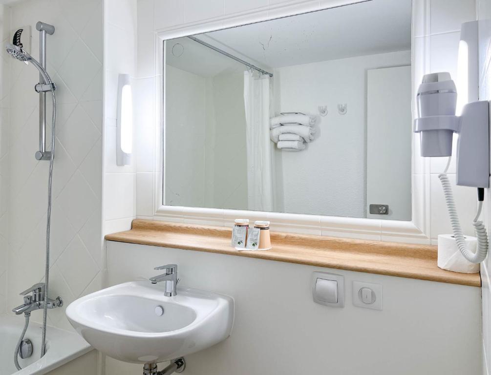 a white bathroom with a sink and a mirror at Kyriad Cannes - Mandelieu in Cannes