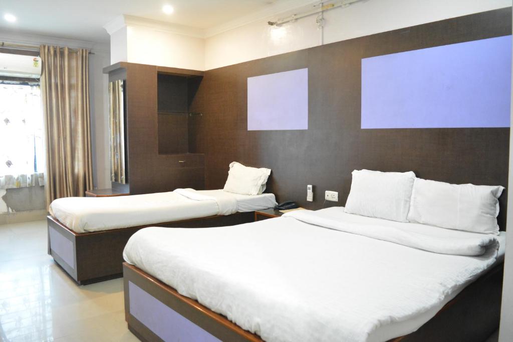 two beds in a hotel room with white sheets at HOTEL SHIVA in Guwahati
