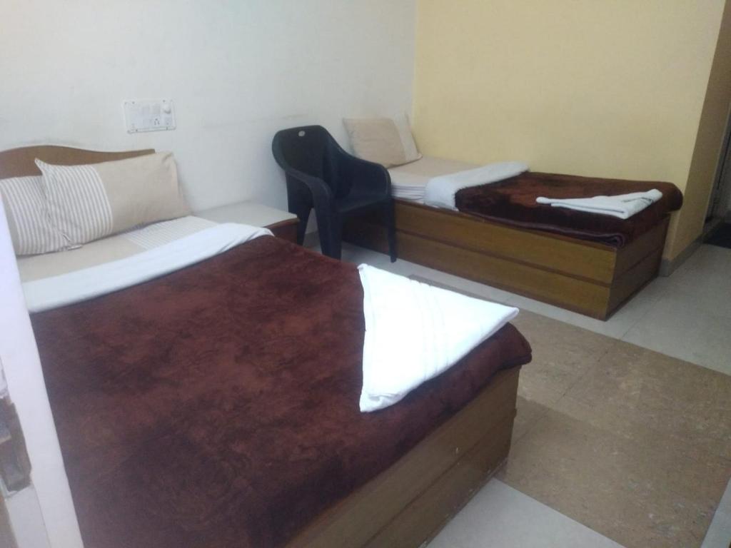 Habitación con 2 camas y una silla. en MYSORE MAHALAKSHMI ROOMS en Mysore