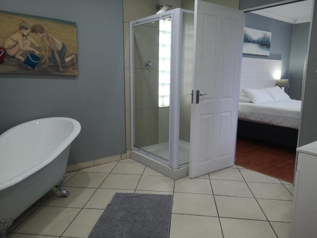 a bathroom with a shower and a tub and a bed at Sky Holiday House in East London