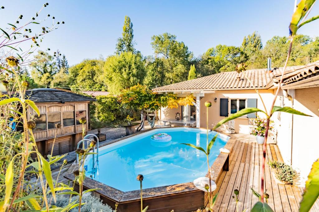 a swimming pool in a backyard with a wooden deck at Petit coin de paradis Périgourdin in Montrem