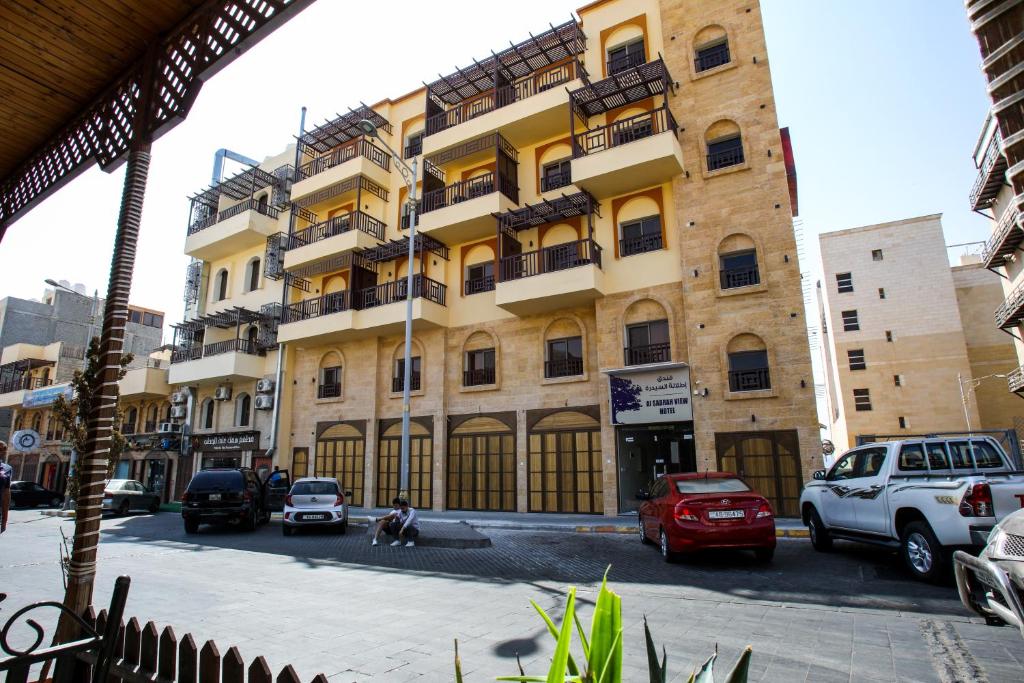 アカバにあるAl Sadrah View Hotel-فندق اطلالة السدرةの車が目の前に停まった大きな建物