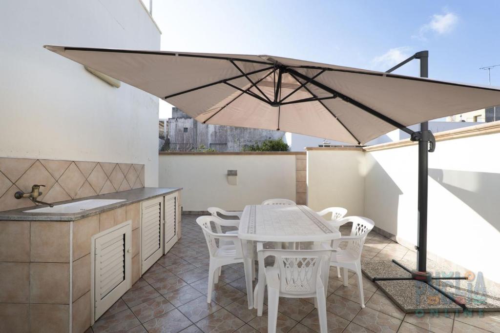 Casa vacanza Lucia Puglia On line في مورتشانو دي ليوكا: فناء مع طاولة وكراسي ومظلة