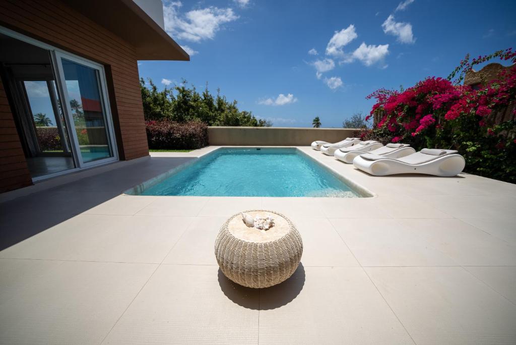 SandBank View Villa - Private Pool- ZanzibarHouses في كيوينجوا: حمام سباحة مع قبعة من القش بجوار منزل