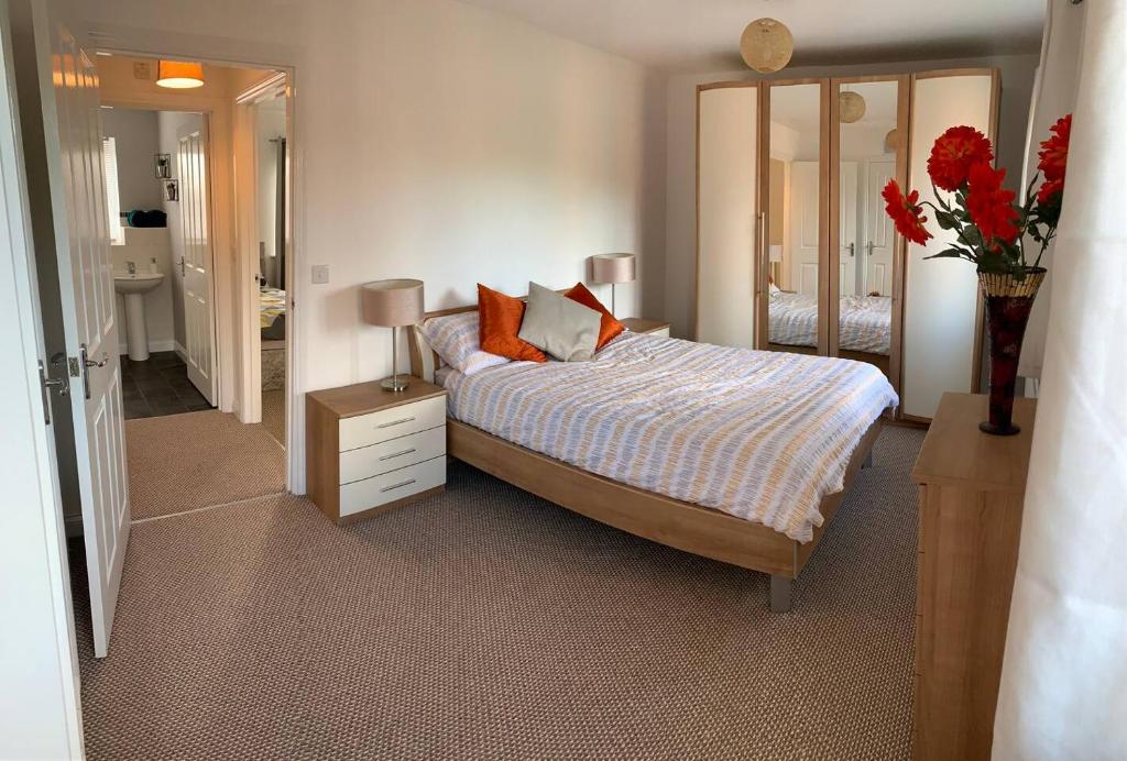 a bedroom with a bed and a vase of red flowers at Aidan House by Blue Skies Stays in Middlesbrough