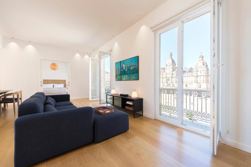 a living room with a blue couch and large windows at Lux Maria Pita Corazon de Coruña in A Coruña