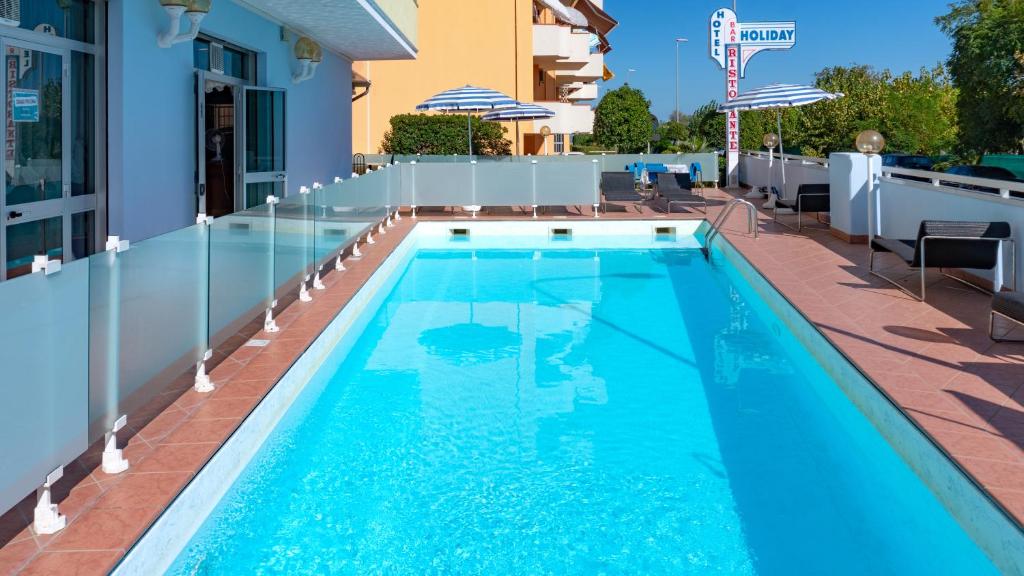 a swimming pool with blue water in a building at Hotel Holiday in Martinsicuro