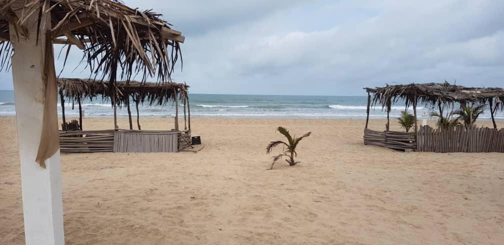 a beach with a straw umbrellas and the ocean at SANYANG in Sanyang