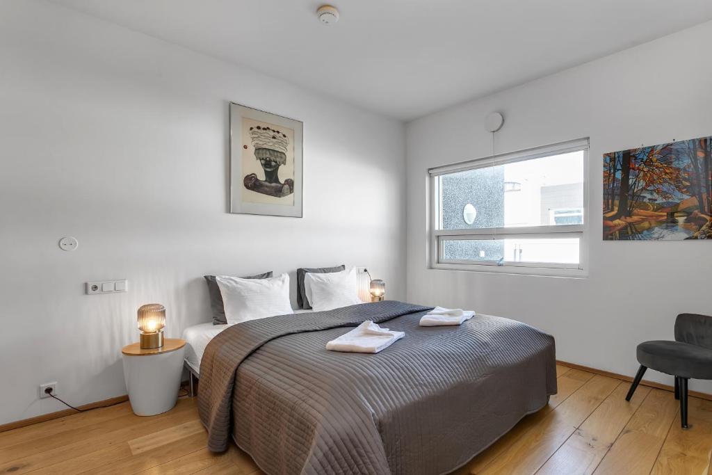 a white bedroom with a bed and a window at Baldursbrá Apartment Laugavegur in Reykjavík