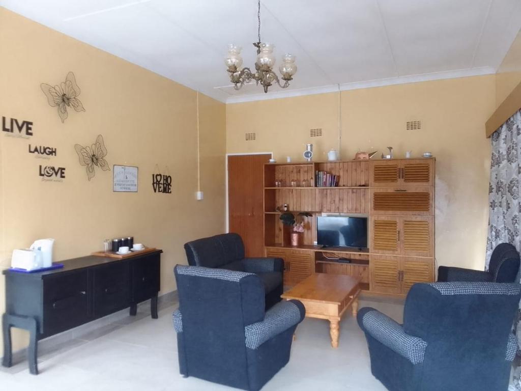 ein Wohnzimmer mit Stühlen, einem Tisch und einem TV in der Unterkunft Holope Self-Catering Accomm in Prieska