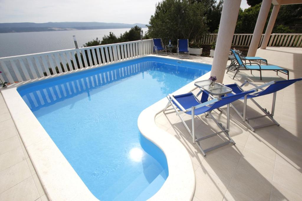 einen Pool mit zwei blauen Stühlen und Wasser in der Unterkunft Apartments Ivančić in Mimice