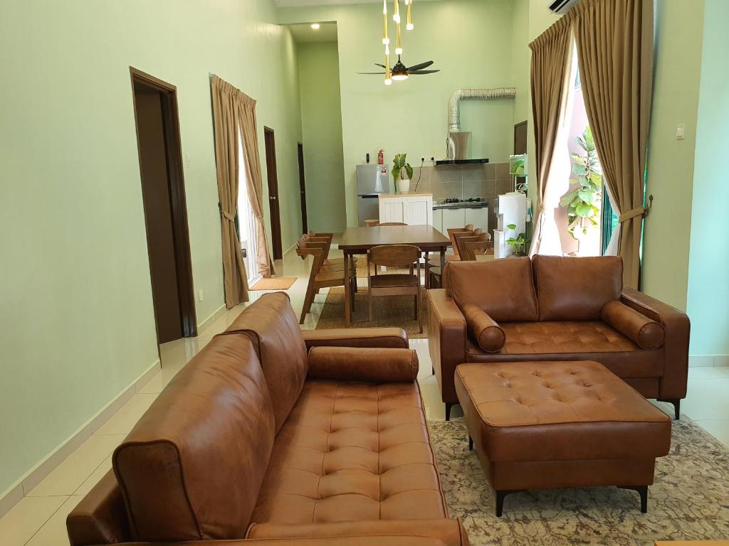 uma sala de estar com um sofá, cadeiras e uma mesa em Duyong Damai Homestay by KOWBMAS em Malaca