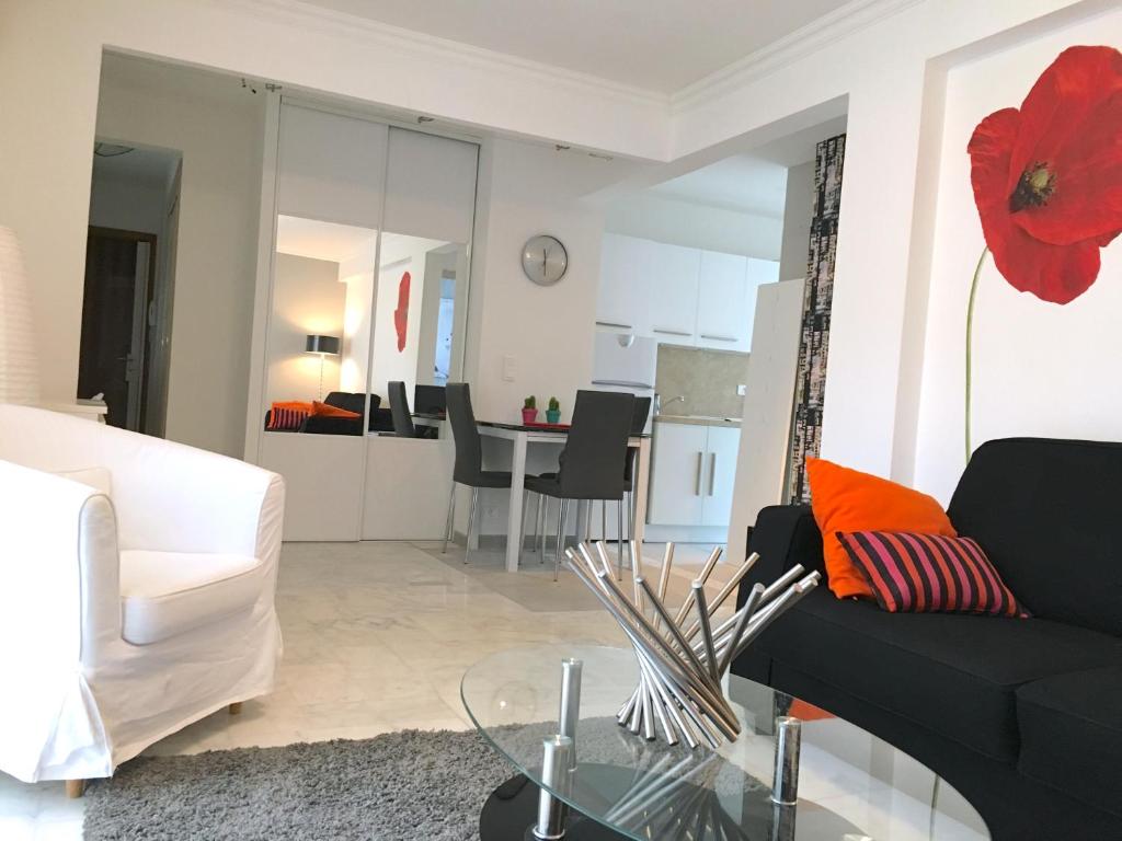ein Wohnzimmer mit einem schwarzen Sofa und einer roten Blume in der Unterkunft Palais Lumière in Cannes