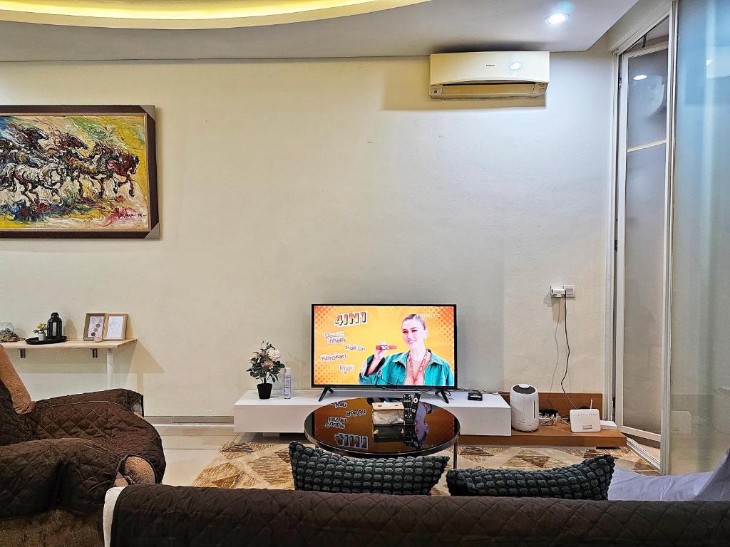 a living room with a couch and a flat screen tv at Aksara de jiva at Pakuwon Indah Cluster in Surabaya