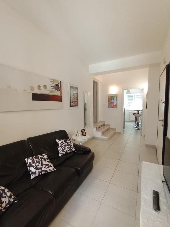 Maison G في لاكويلا: غرفة معيشة مع أريكة سوداء وأرضية بيضاء