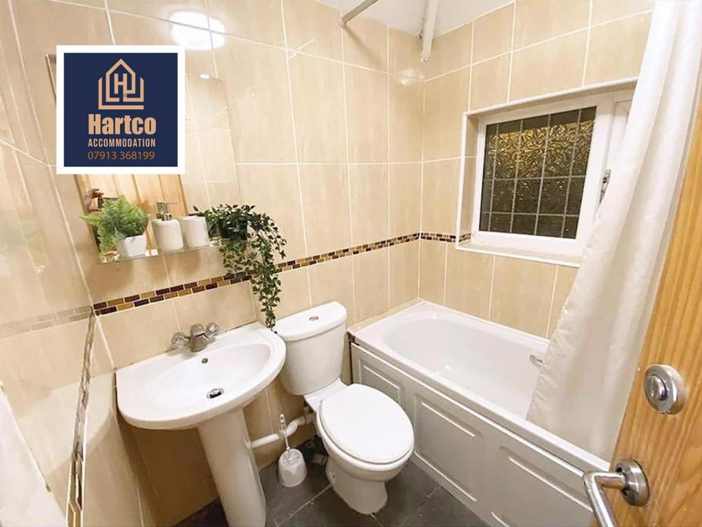 a bathroom with a toilet and a sink and a tub at Botany House - Company & Family Stays in Bescot