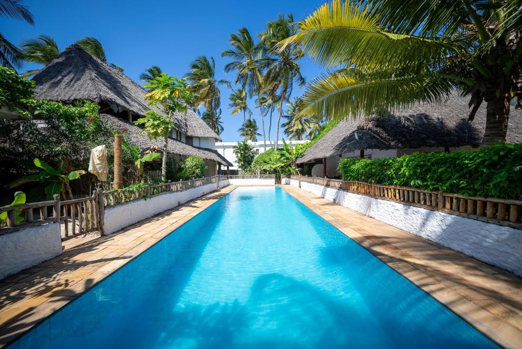 a swimming pool at a resort with palm trees at Villa Jiwe with Pool ZanzibarHouses in Kumba Urembo