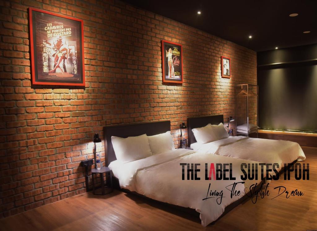 a bedroom with a bed and a brick wall at The Label Suites Ipoh in Ipoh