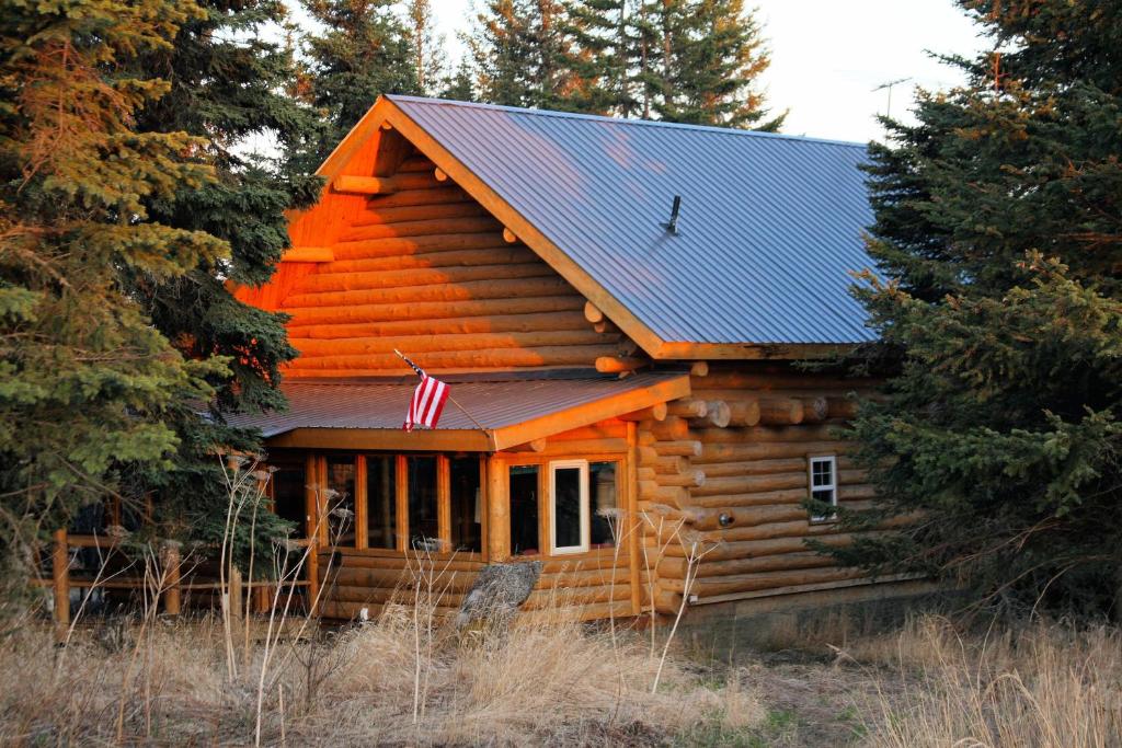 a log cabin with an american flag on it at Wise Old Hunter Lodge in Anchor Point