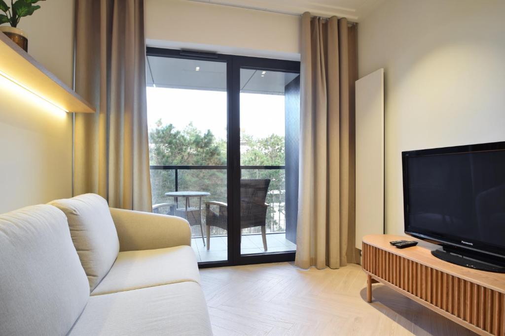 un salon avec un canapé blanc et une télévision dans l'établissement RentPlanet - Apartamenty Shellter, à Rogowo