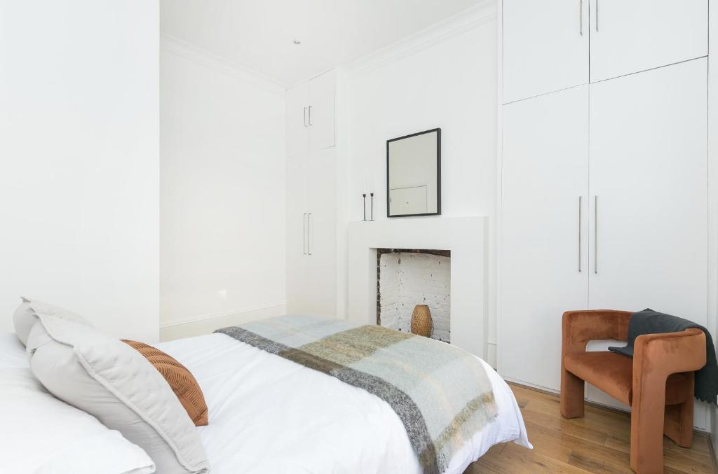 a white bedroom with a bed and a chair at Sun drenched 1 bedroom apartment in Farringdon in London