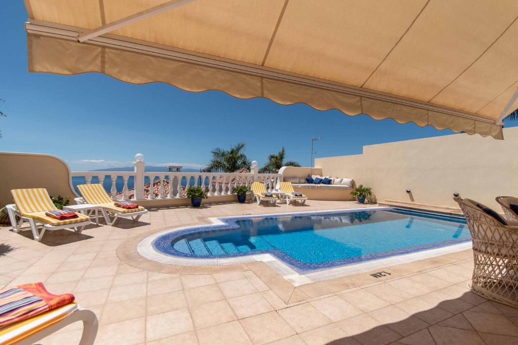 - une piscine sur une terrasse avec des chaises et un parasol dans l'établissement Villa Vista Gomera, à Puerto de Santiago