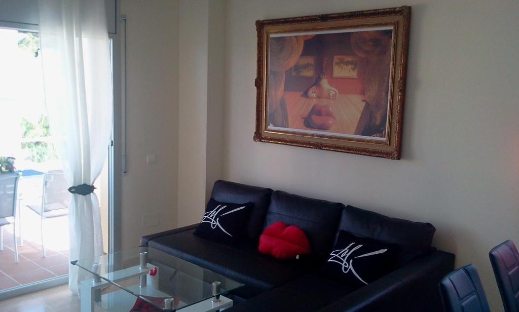 ein Wohnzimmer mit einem schwarzen Sofa und einem Bild in der Unterkunft Dalí Apartment in Llança