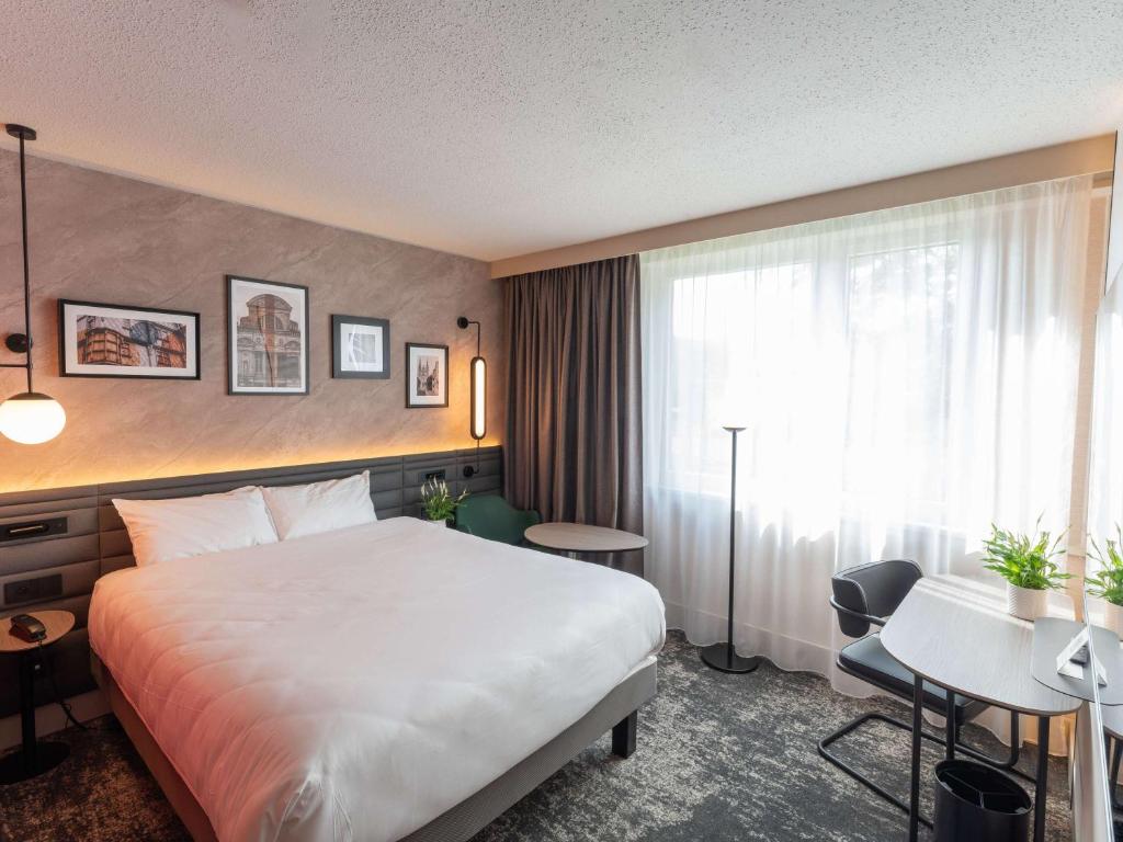 昂熱的住宿－昂熱曼恩湖美居酒店，酒店客房设有一张大床和一张书桌。